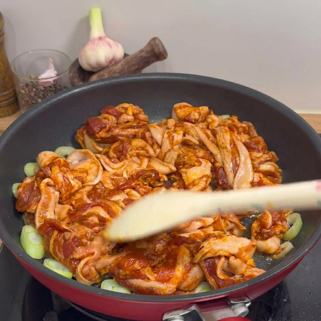木べらを使って、豚肉とねぎをこんがりとするまで炒め合わせている様子。