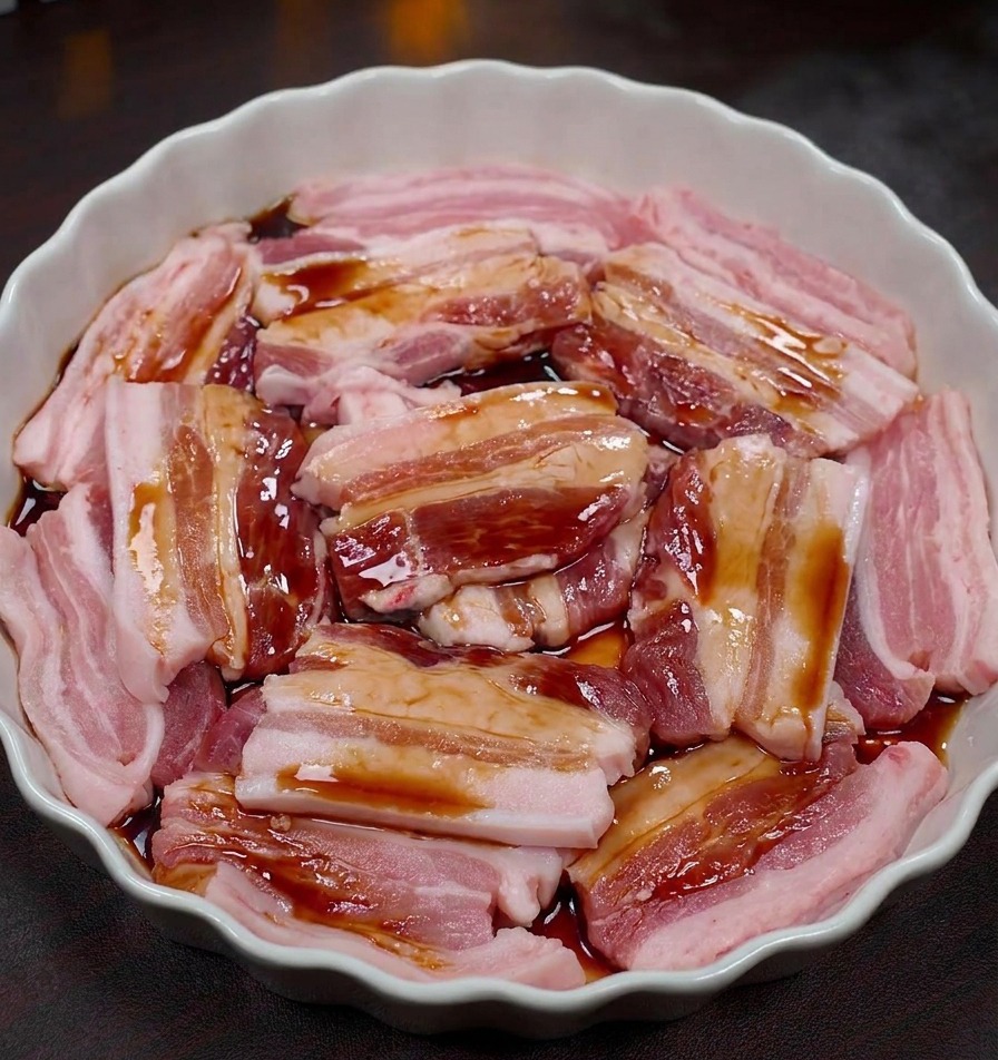 醤油ベースのタレを豚バラ肉に絡めている様子