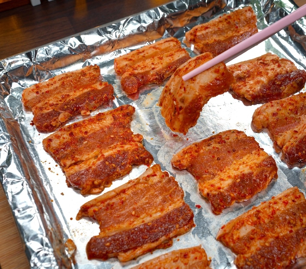 アルミホイルを敷いた天板に箸で肉を並べている様子