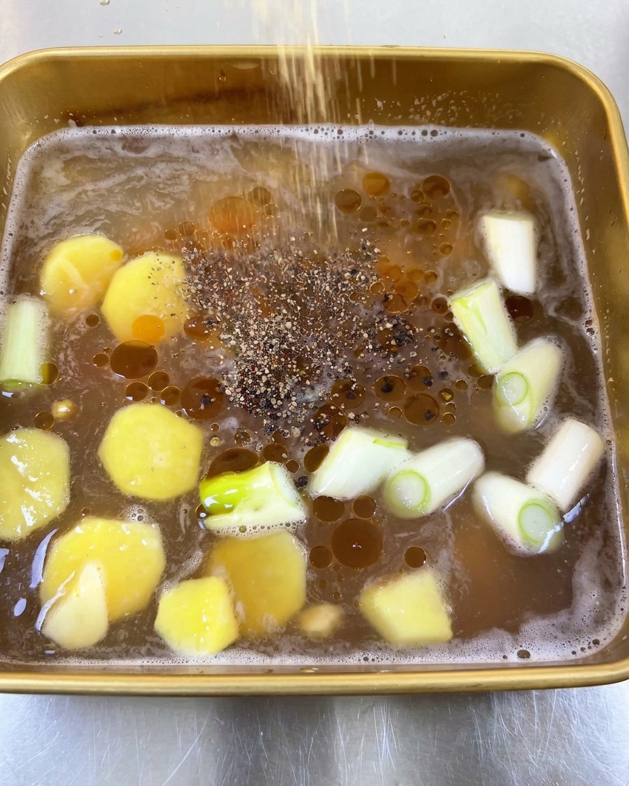 油の浮いたマリネ液に、黒こしょうを振り入れている様子。