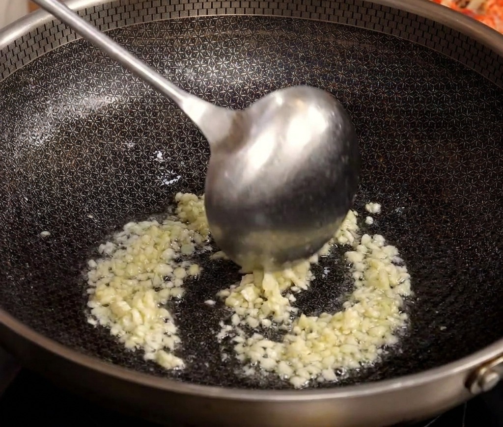 熱した中華鍋で、刻んだにんにくを油で炒めている様子。