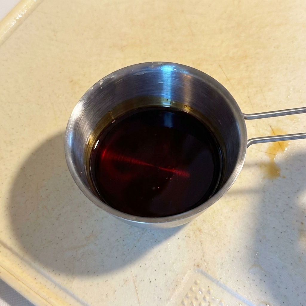 小さな計量カップに入った、醤油ベースの艶やかな合わせ調味料。