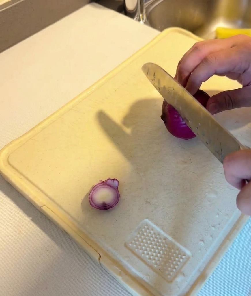 まな板の上で紫玉ねぎを薄くスライスしている様子。