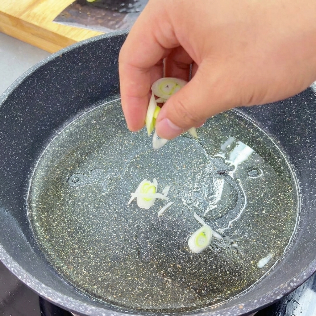 フライパンに敷いた油で、刻んだ長ねぎを炒めて香りを立たせている様子。