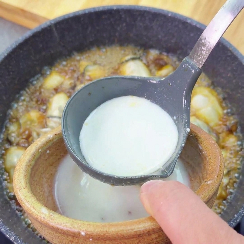 煮立つ牡蠣料理に、白い水溶き片栗粉をお玉で回し入れながらとろみをつけている様子。