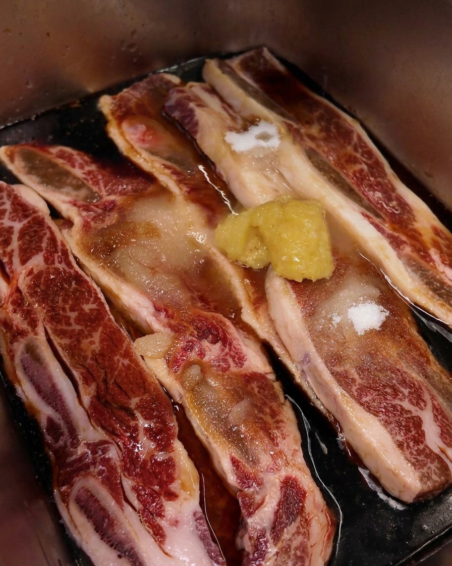 醤油ベースのタレに浸かった牛リブの上に、たっぷりのおろしにんにくが乗っている様子。