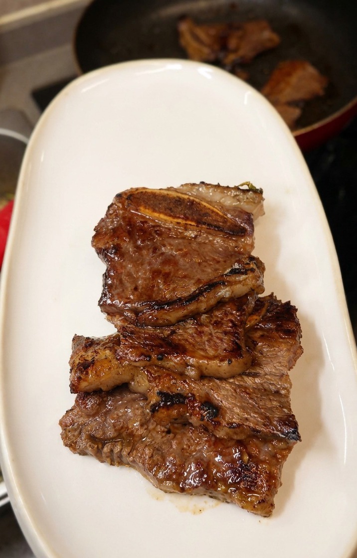 艶やかな茶色に焼き上がったLAカルビを、細長い白い皿に盛り付けている様子。