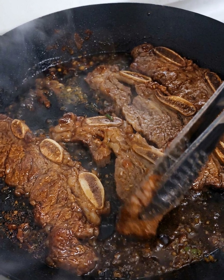 泡立つタレの中で肉をトングで返し、艶やかな照りが出ている様子。