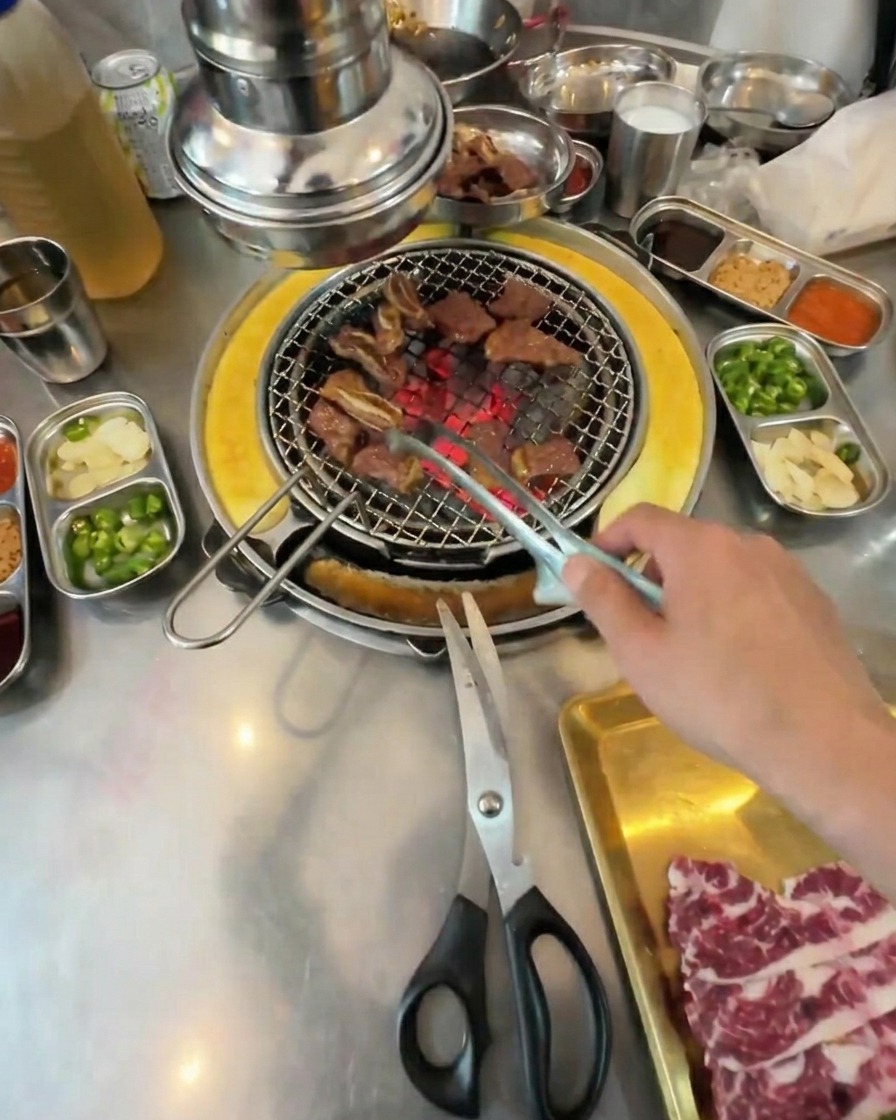 網の上で一口サイズに焼けた肉をトングで転がしながら仕上げている様子。