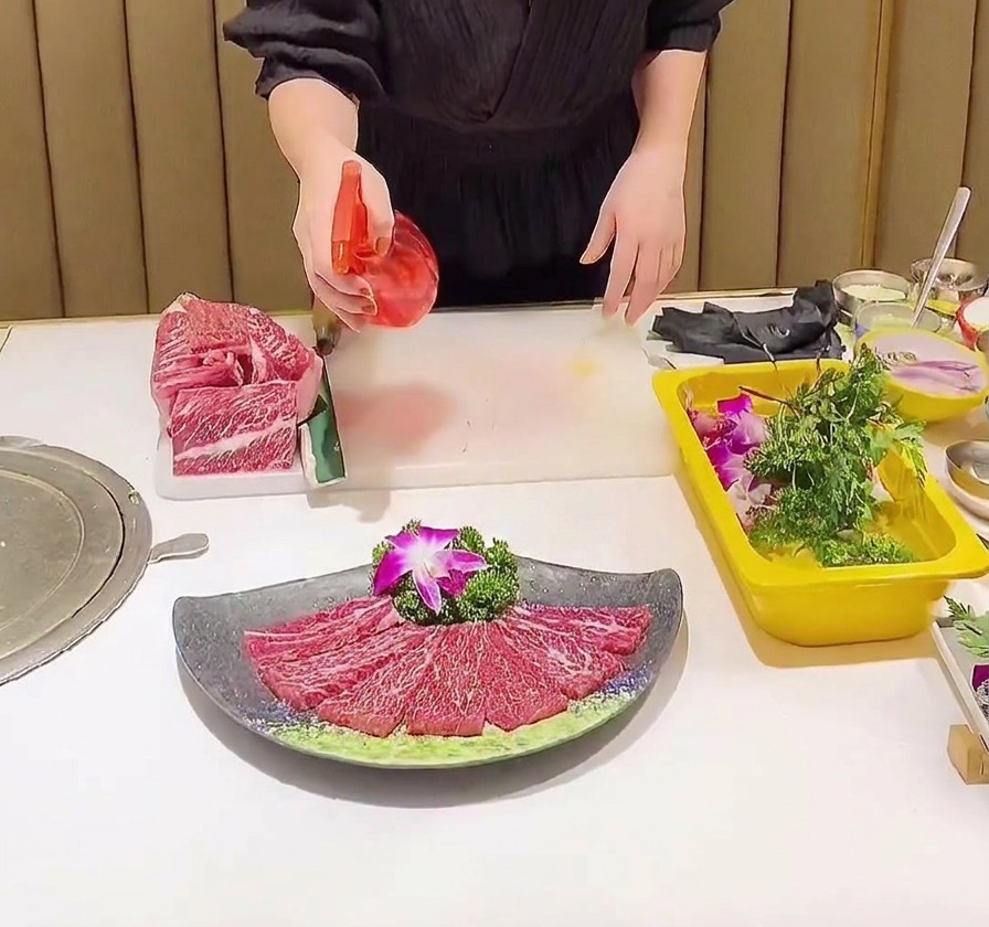 スプレーボトルを使って、塩を振った霜降り肉に透明な液体をミスト状に吹きかけている様子。