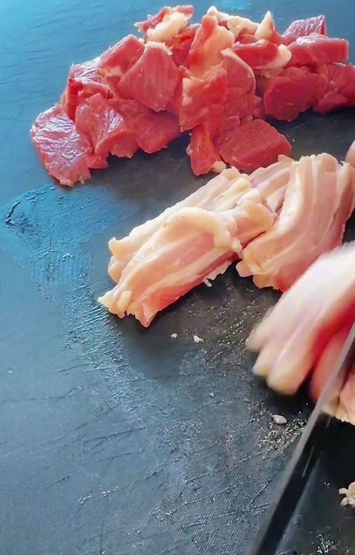 まな板の上で豚バラ肉を一口大の食べやすい大きさに切っている様子。