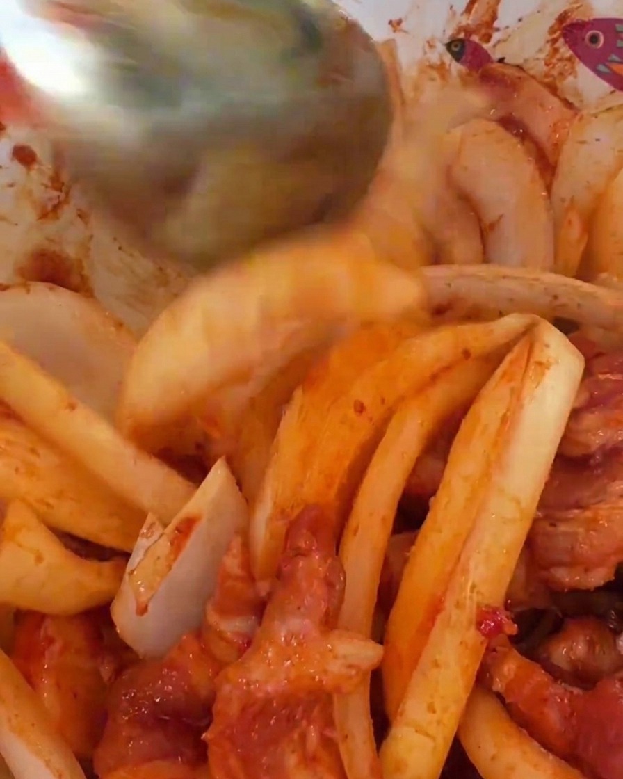 スライスした玉ねぎを味付けした豚肉に混ぜ合わせている様子。