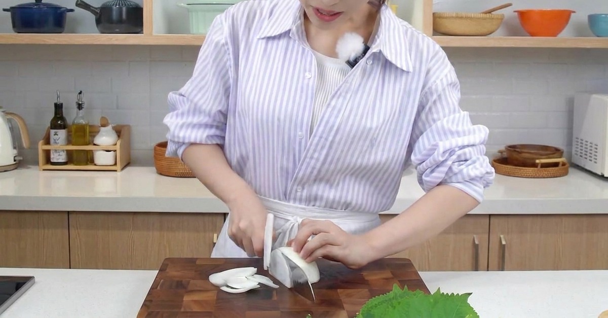 まな板の上で玉ねぎを薄い串切りにしている様子。