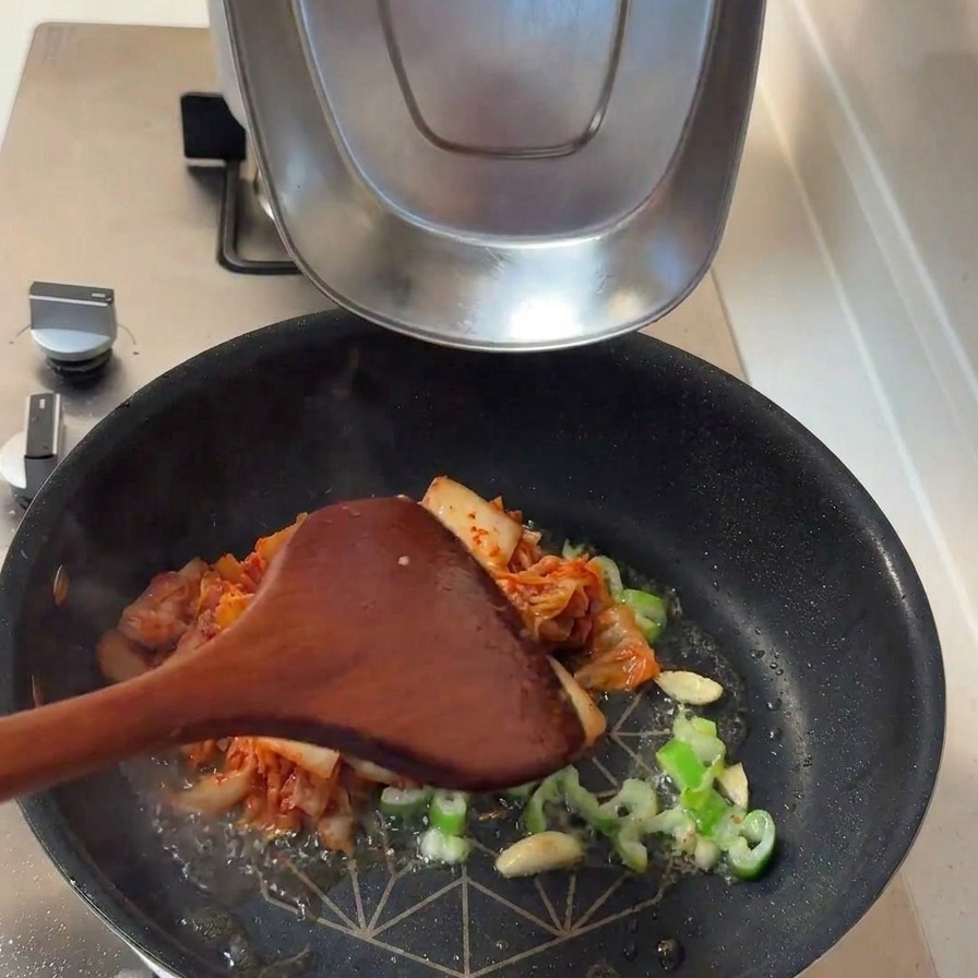 炒めた香味野菜に、たっぷりのキムチとスライスした玉ねぎを投入した様子。