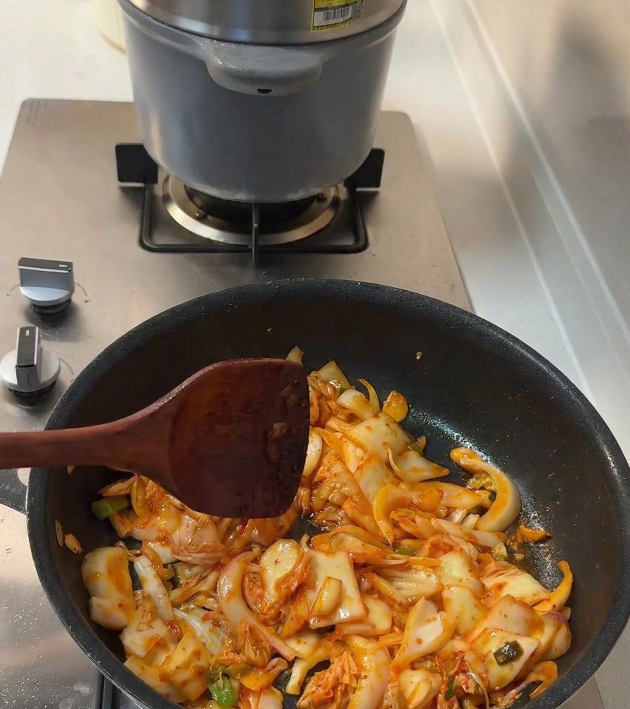 炒めている具材に、醤油と砂糖を振り入れている様子。