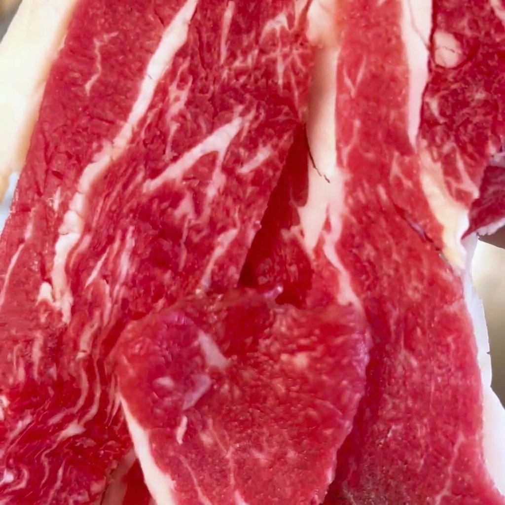 ステンレス製のボウルに入れられた、サシの入った新鮮な牛薄切り肉。