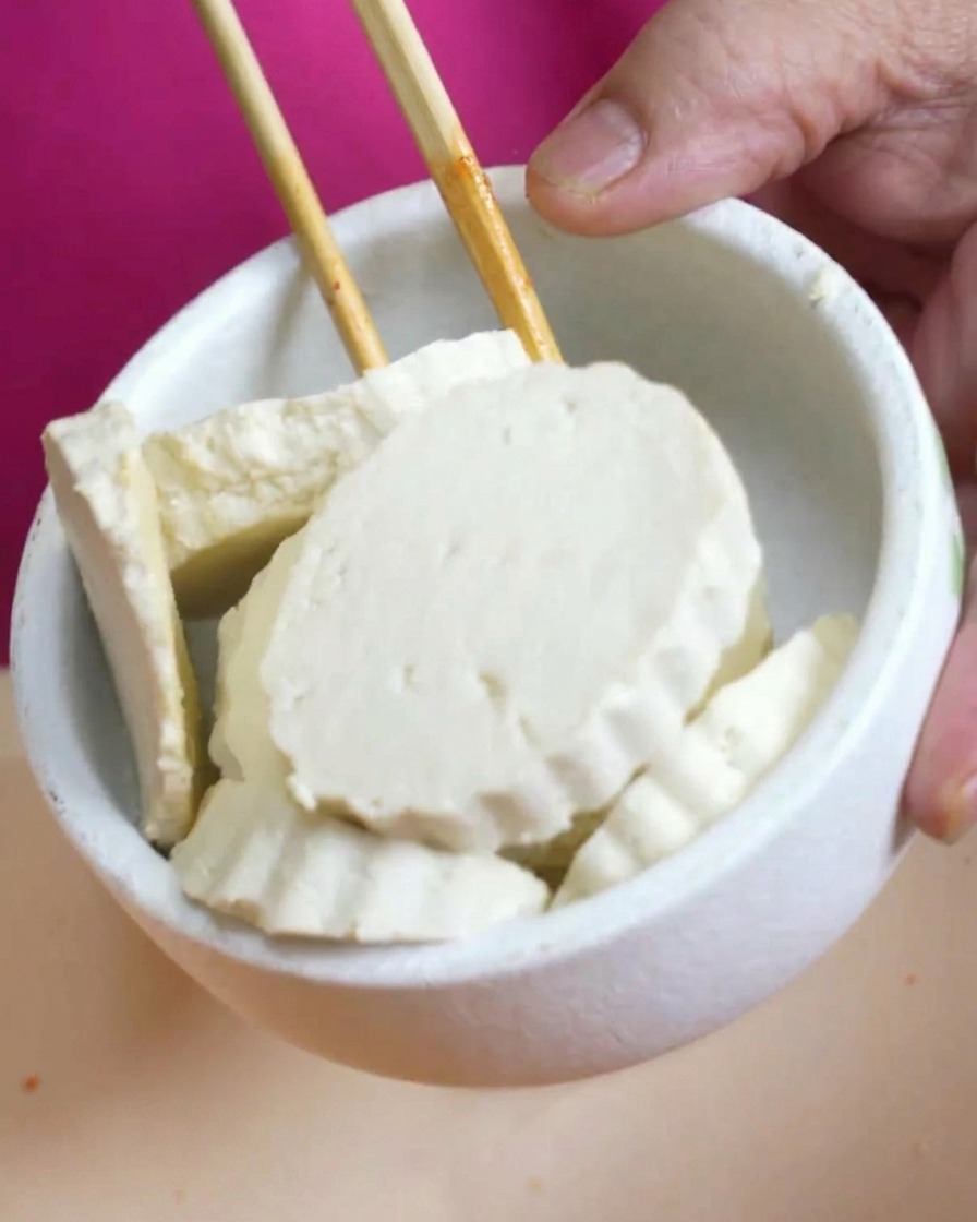 厚切りにされた白い豆腐を鍋にそっと並べている様子。