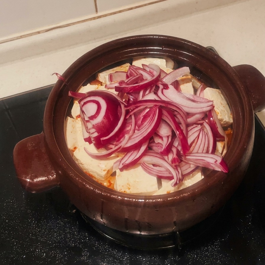豆腐の上にスライスした赤玉ねぎを重ねている様子。