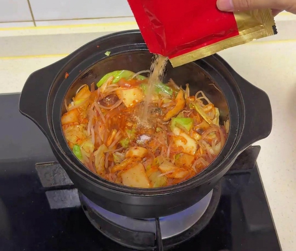 鍋の中に牛だしの粉末を振り入れている様子。