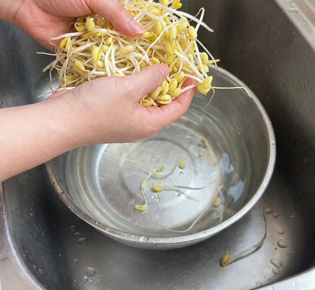 ステンレスボウルの中で豆もやしを流水で洗っている様子