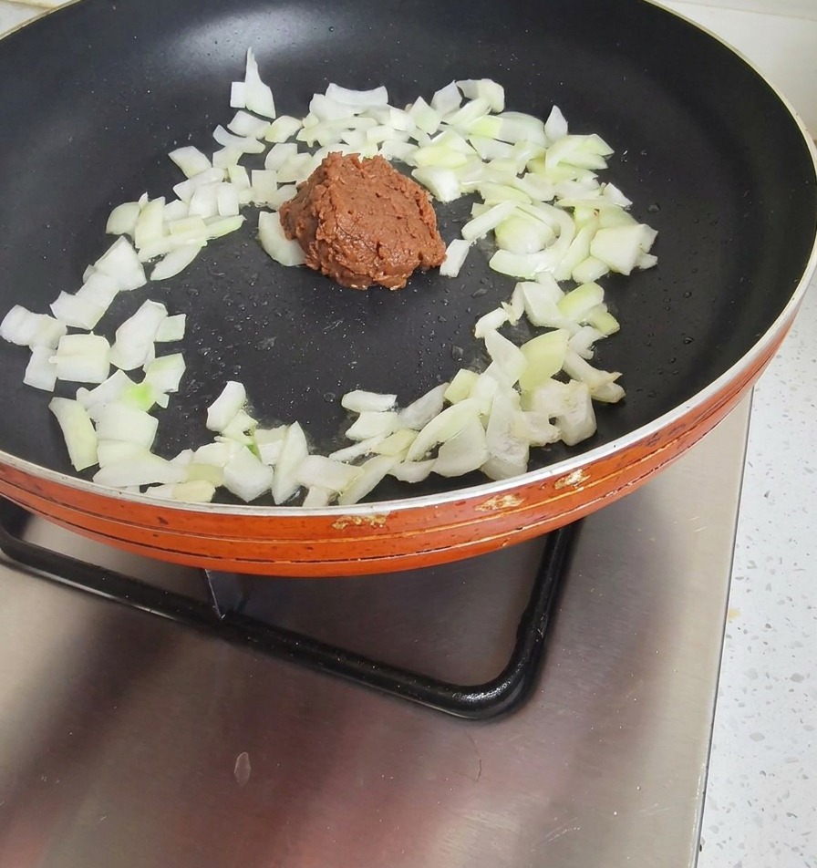 炒めた玉ねぎに韓国味噌を加えている様子