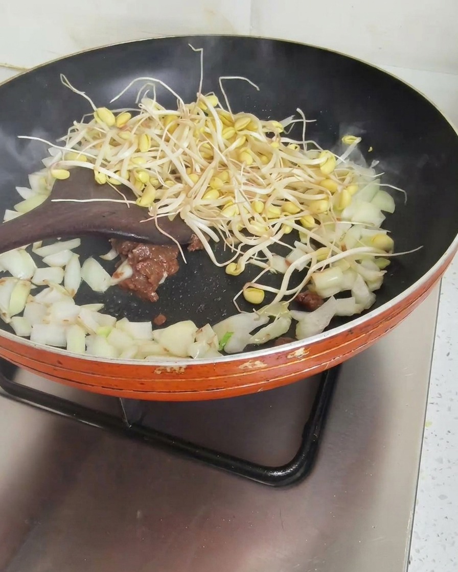 味噌と玉ねぎの中に豆もやしを加えて混ぜ合わせている様子