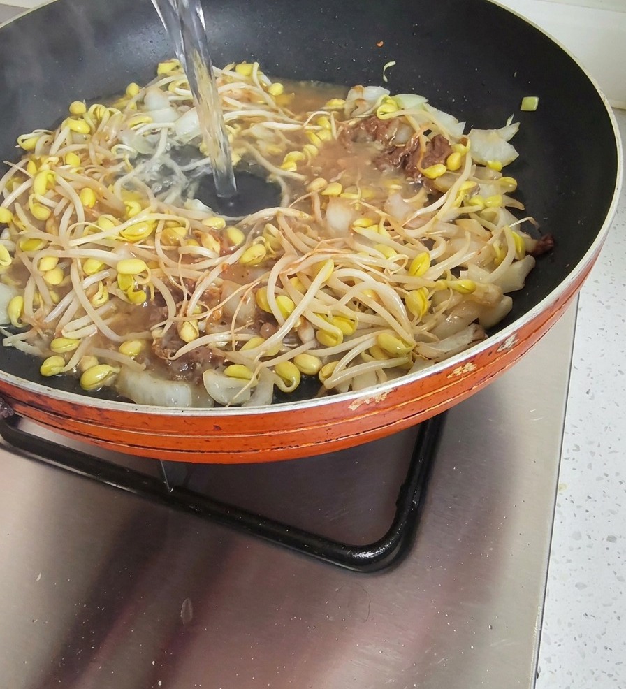炒めた具材の中に水を注ぎ入れている様子