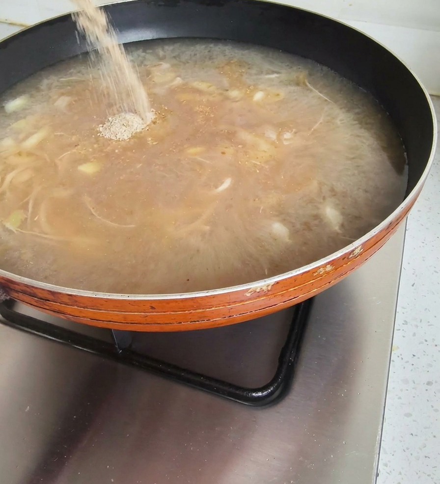 煮立っているスープに粉末調味料を加えている様子