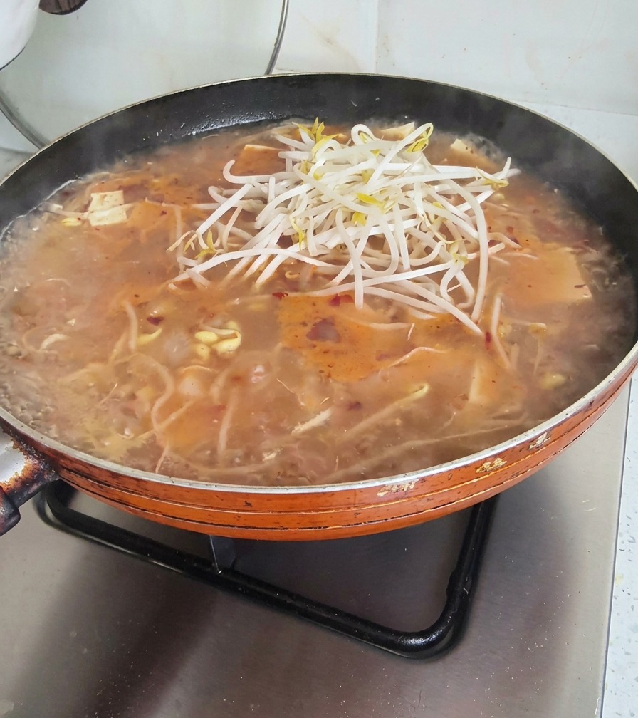 スープの上にさらに豆もやしと青菜を乗せている様子