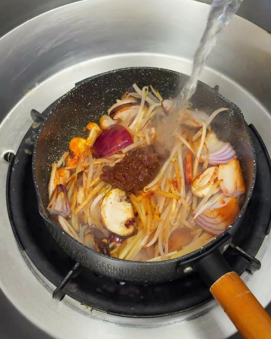 野菜と味噌が入ったフライパンに、熱湯が注がれている様子。