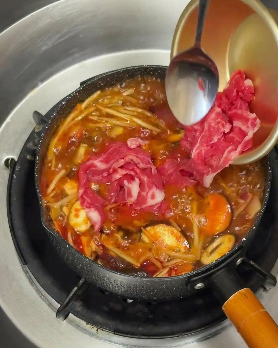 沸騰した赤いスープの中に、薄切りの牛肉を入れている様子。