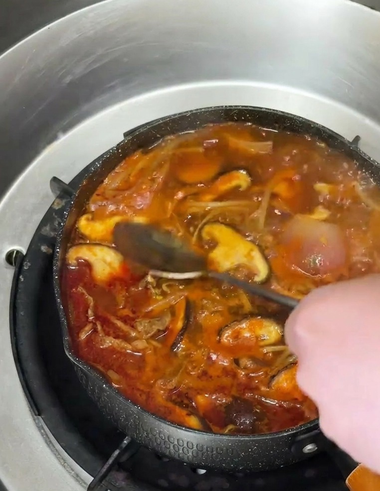 スープの表面に、スプーンから香ばしいごま油を回しかけている様子。