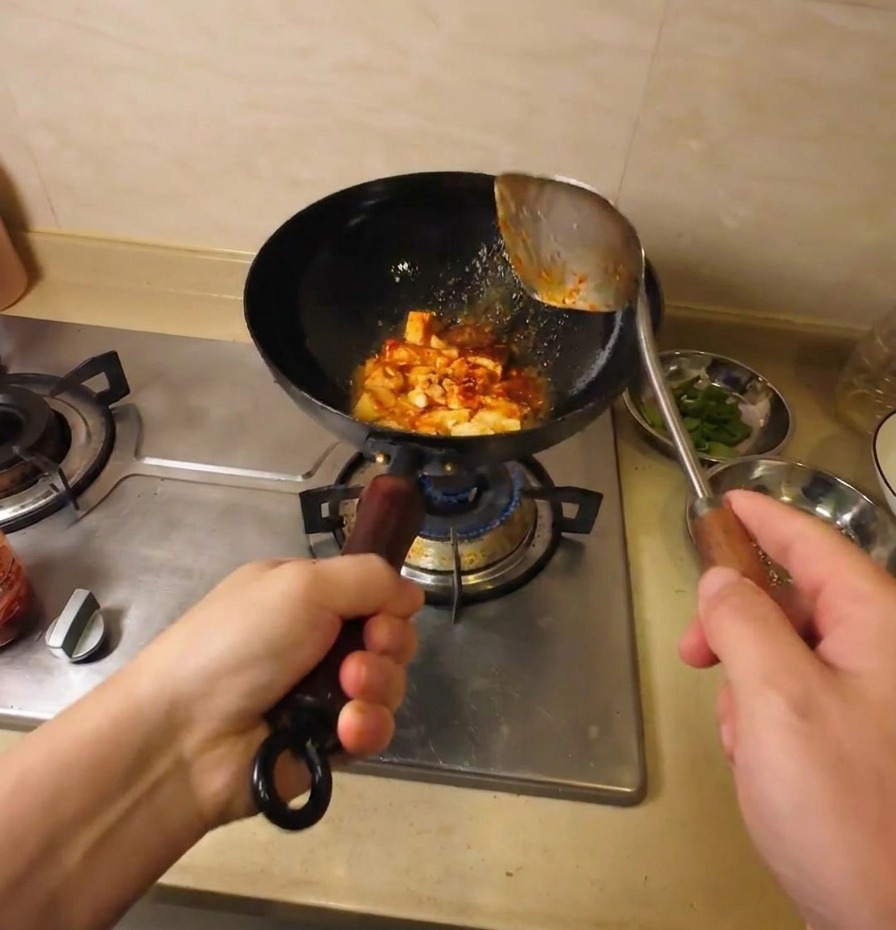中華鍋の中で豆腐に赤いソースと味噌がしっかり絡んでいる様子。