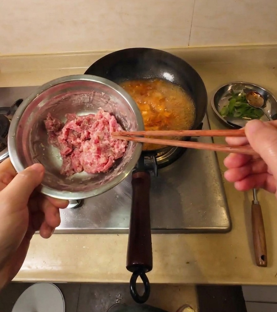 沸騰したスープに、澱粉をまぶした牛ヒレ肉を箸で1枚ずつ入れている様子。