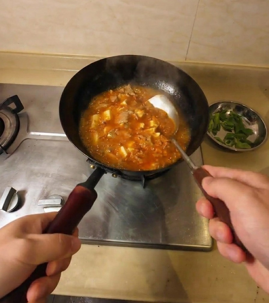 牛肉と豆腐が入ったスープがグツグツと煮立ち、少しとろみがついている様子。