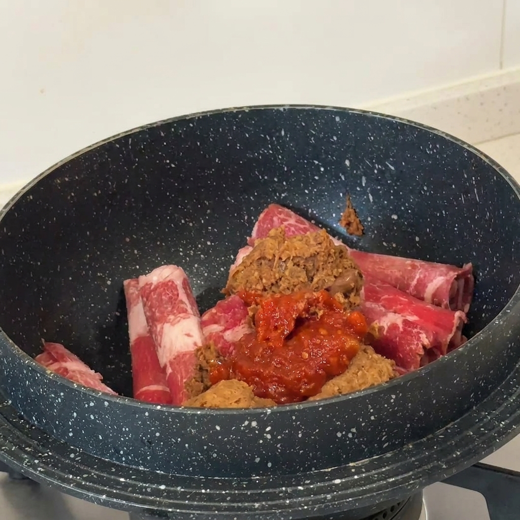 鍋に入った生の牛肉の上に、テンジャンとコチュジャンが乗っている様子