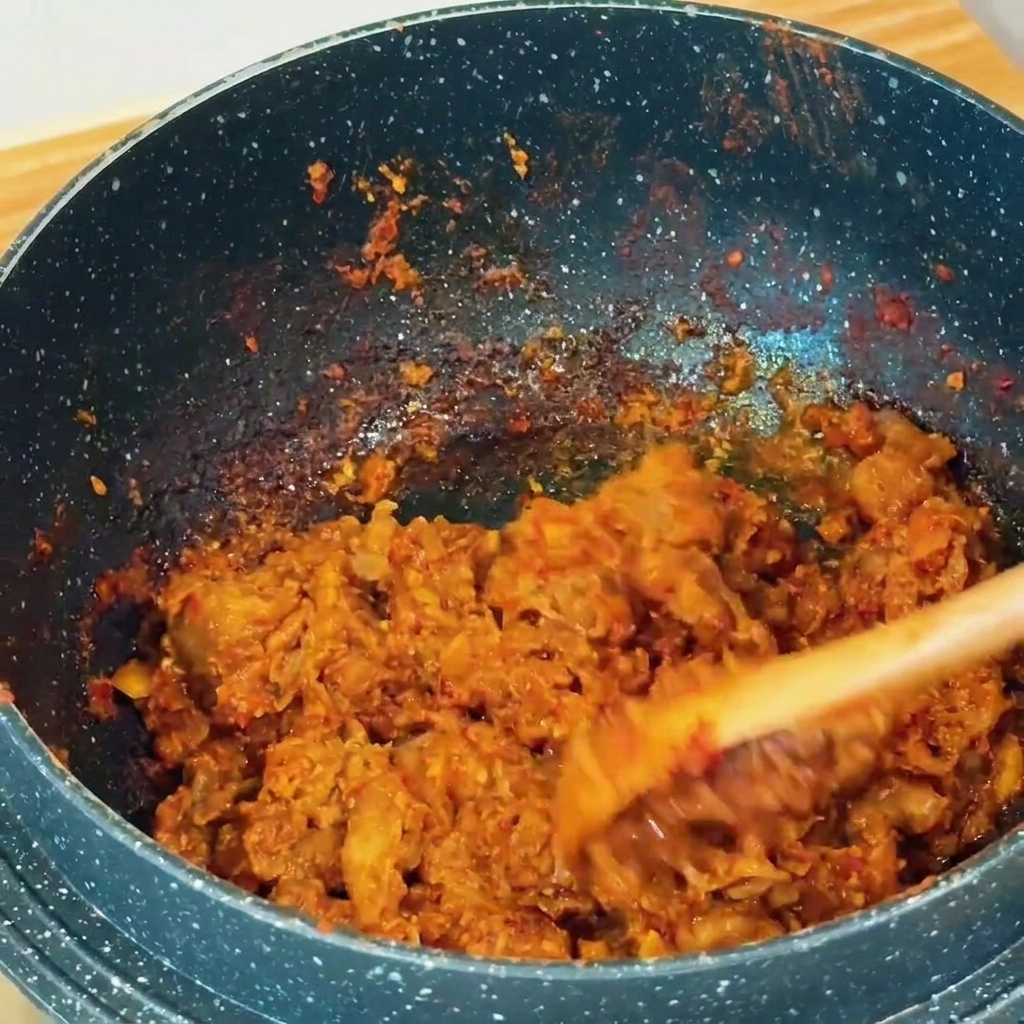 木べらを使って、鍋の中で牛肉と味噌を炒め合わせている様子