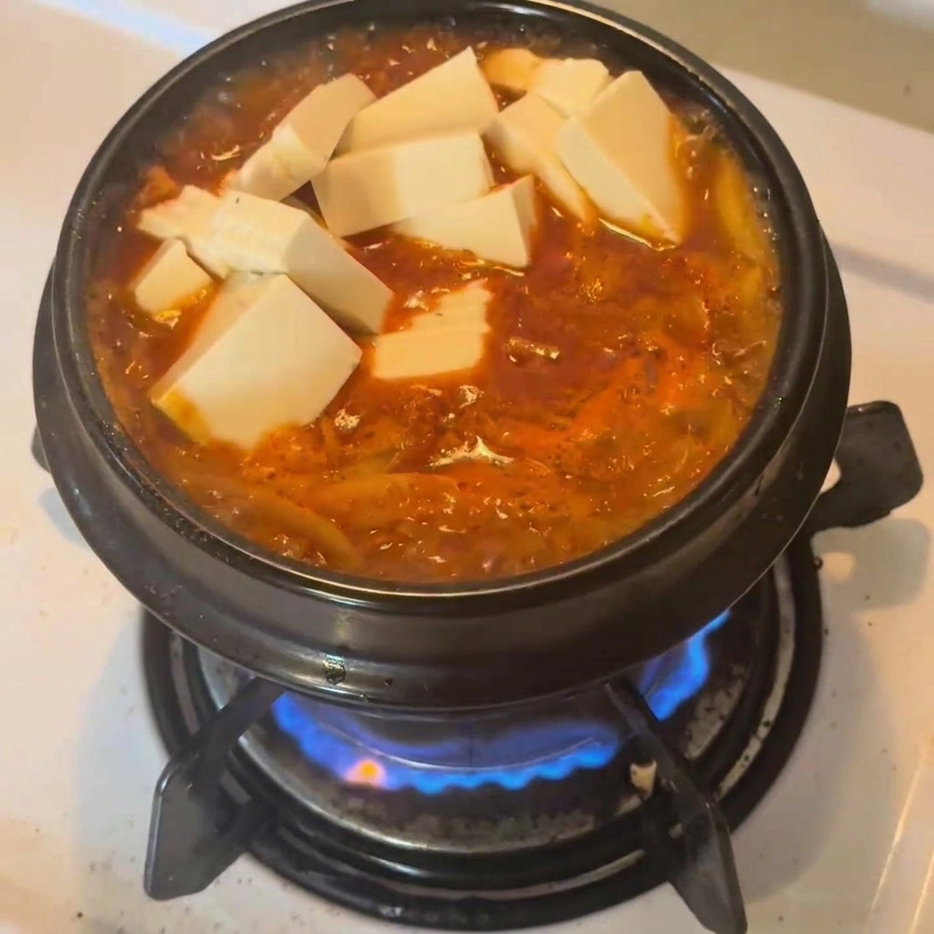 真っ赤なスープの上に、白い豆腐の角切りをのせている様子。