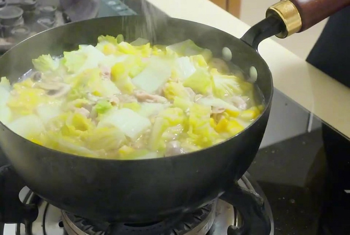 煮込んでいるスープに塩を振りかけて味を調えている様子。