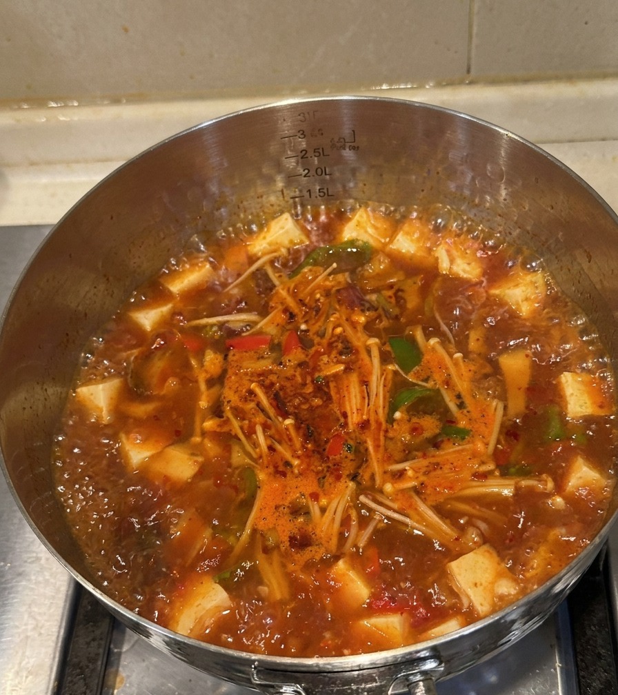 肉、えのき、ピーマンが煮えた、熱々のキムチ牛肉スープが完成した様子。