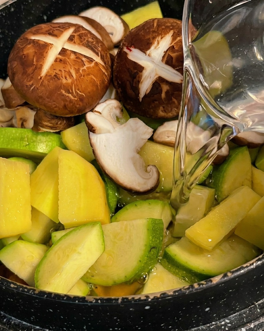 鍋の野菜の上から水を注ぎ入れている様子。
