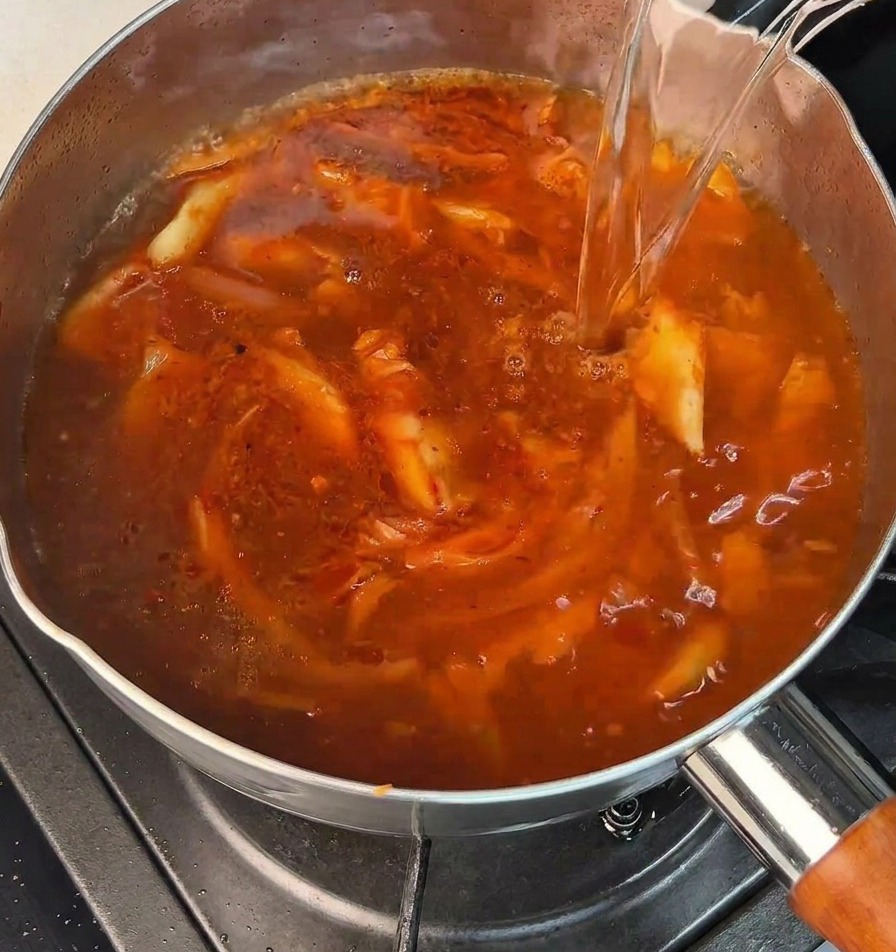 沸騰したお湯を赤いスープのベースに注いでいる様子