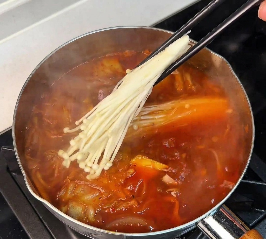 箸でえのき茸をスープに入れる様子