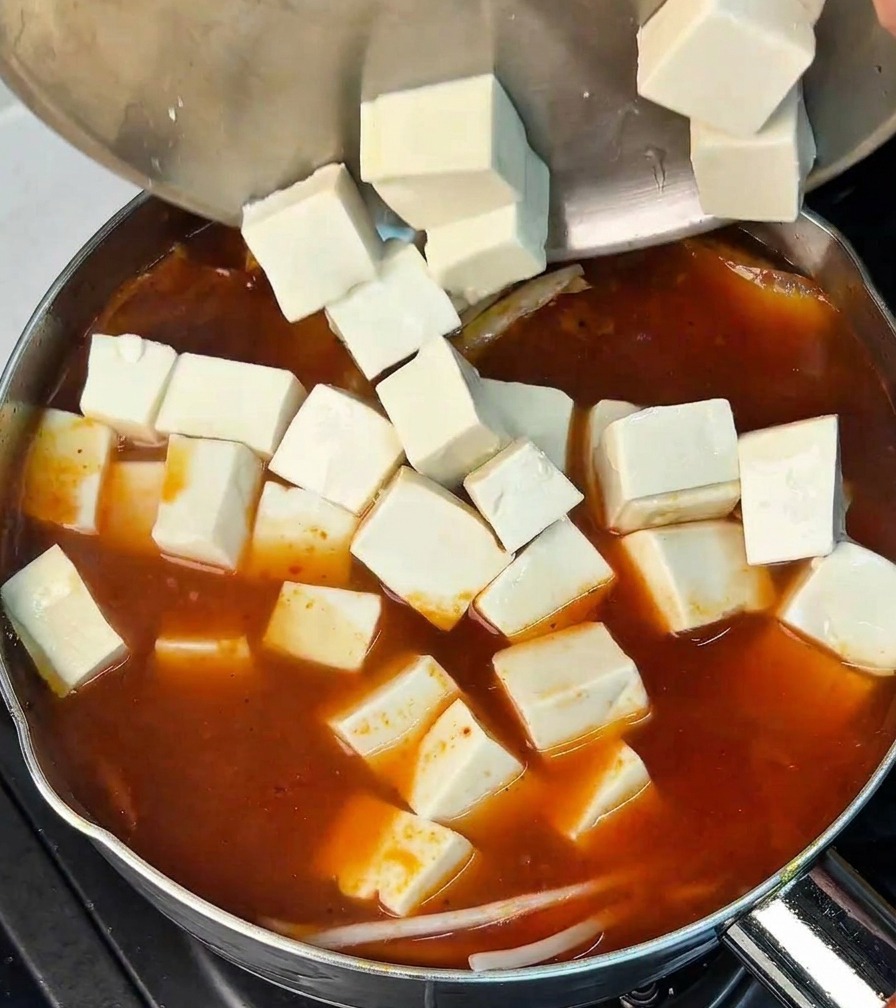 ボウルから豆腐を鍋に静かに移している様子