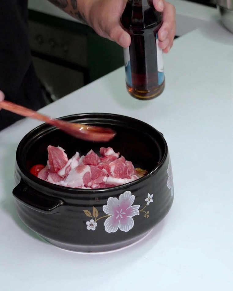 スプーンにナンプラーを注ぎ、鍋の具材の上に加えている様子