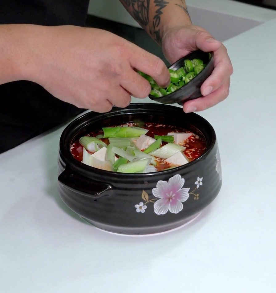仕上げに刻んだ青唐辛子を豆腐の上にトッピングしている様子