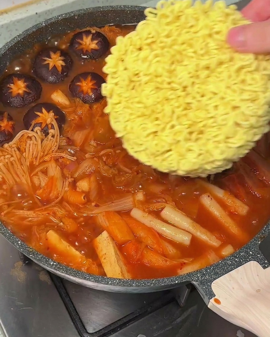 沸騰したスープの中に、インスタントラーメンの乾麺を入れている様子