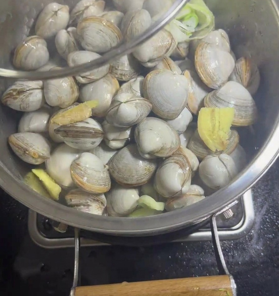 ガラス蓋をしっかり閉めた鍋の中で蒸されているハマグリ。