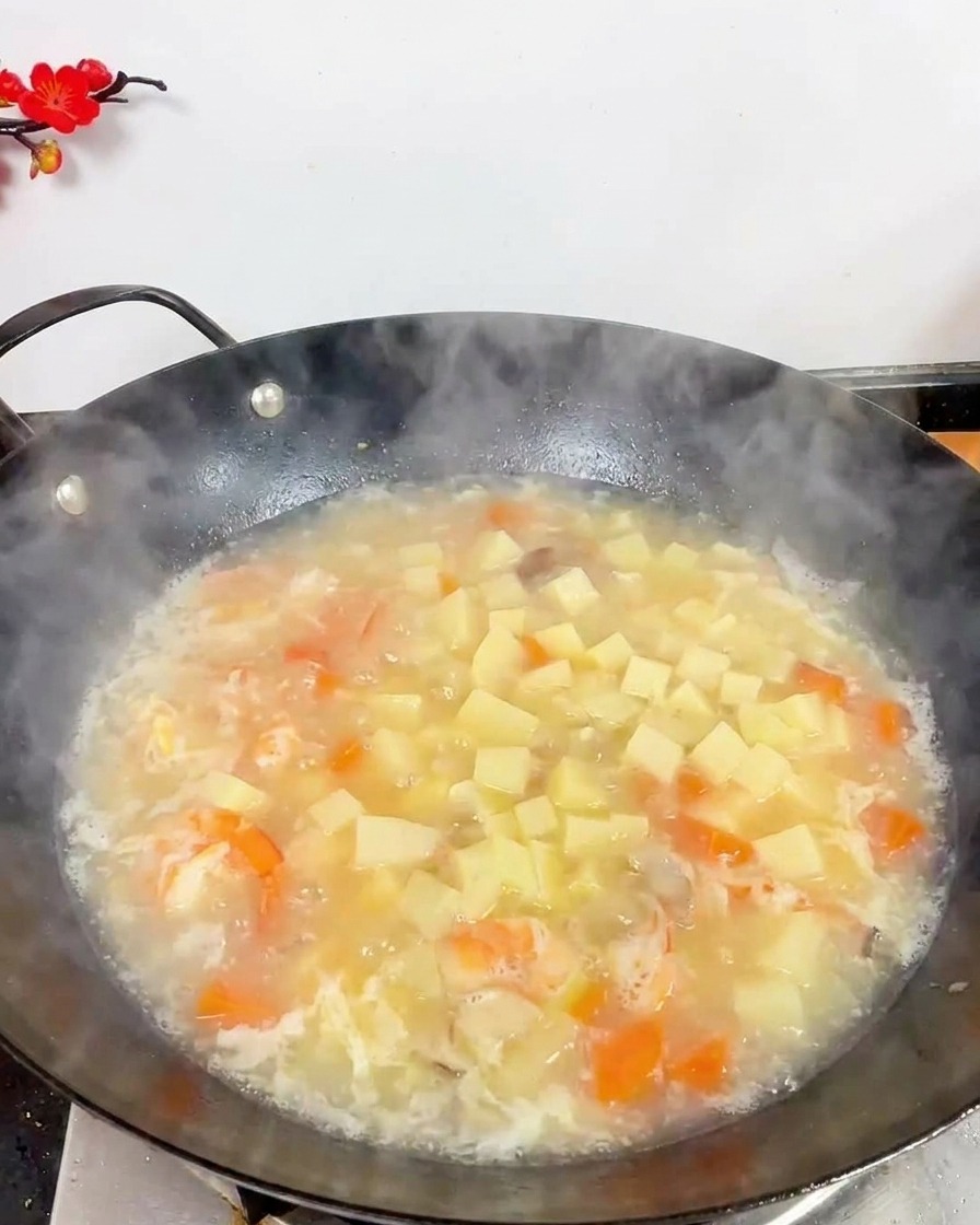 白いスープの中に豆腐、エビ、茶色のしめじが入り、煮立っている様子を上から見た図。