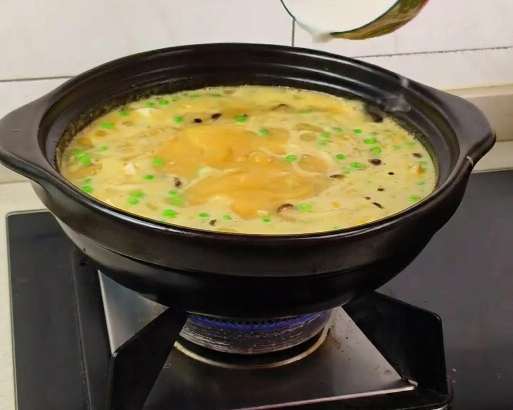 煮立ったスープに水溶き片栗粉を回し入れ、とろみをつけている手元。